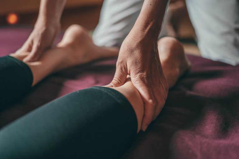 close up of woman on physical therapy table getting work on her calves by the physical therapist