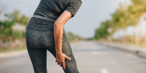 Close up of runner in the road holding their hamstring