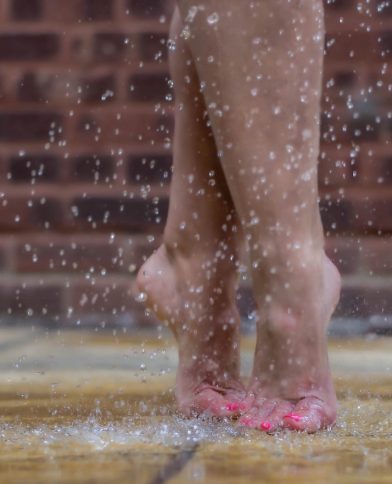 Dancer's feet in relevé fifth position with hot pink toe nail polish in the rain